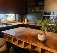 Kuchyně v 2pokojovém bytě s podlahou s dřevěným dekorem a černou kuchyňskou linkou.