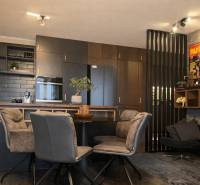 Kuchyně v 2-pokojovém bytě s tmavými skříňkami a dekorativními plakáty na stěně.