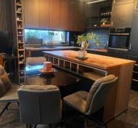 Kuchyně v 2-pokojovém bytě s černými skříňkami a podlahou s dřevěným dekorem.