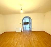 Pokoj s obloukovým průchodem a podlahou s dřevěným dekorem v rodinném domě.