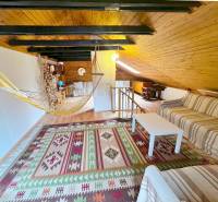 Podkroví chaty s pohovkou, houpací sítí a podlahou s dřevěným dekorem.