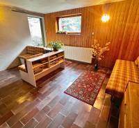 Obývací část v chatě s cihlovou dlažbou a dřevěným dekorem na stěnách.