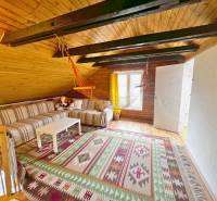 Podkroví chaty s dřevěným stropem, pruhovanou sedačkou a závěsným houpacím křeslem.