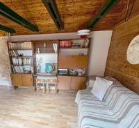 Interiér chaty s dřevěnými trámy, nábytkem a podlahou s dřevěným dekorem.