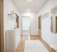 Chodba ve 4-pokojovém bytě s podlahou s dřevěným dekorem, jednoduše zařízená.