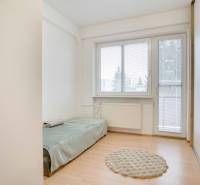 Jednoduchý pokoj s podlahou s dřevěným dekorem a rozkládací postelí ve 4pokojovém bytě.