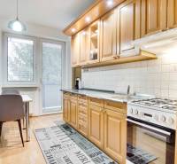 Kuchyně ve 4pokojovém bytě s podlahou s dřevěným dekorem a jídelním stolem.