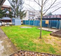 Zahrada u 4pokojového bytu v Kolte, se zelení, chodníkem a houpačkou.