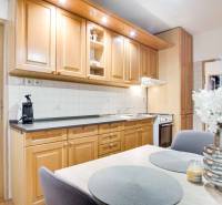 Kuchyně ve 4-pokojovém bytě s dřevěnými skříňkami, květinami a jídelním stolem.