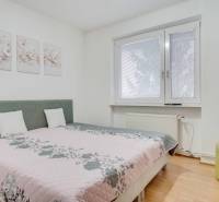 Ložnice ve 4pokojovém bytě s květinovými dekoracemi a televizí na stěně.