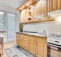 Kuchyně ve 4-pokojovém bytě s podlahou s dřevěným dekorem a jídelním koutem.