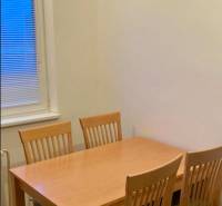 Jídelní stůl se čtyřmi židlemi ve 3pokojovém bytě, podlaha s dřevěným dekorem.