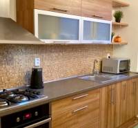 Kuchyně s dřevěným dekorem a vestavěnými spotřebiči ve 3pokojovém bytě.