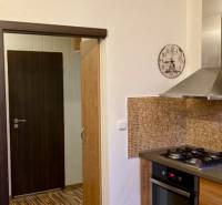 Kuchyně v 3-pokojovém bytě s plynovým sporákem, mozaikovým obkladem a podlahou s dřevěným dekorem.