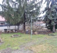 Zahrada u rodinného domu v Kravanoch nad Dunajem s altánkem a jehličnatými stromy.