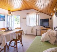 Rekreační apartmán s jídelním koutem, televizorem, otevřeným oknem a dřevěným stropem.