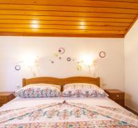 Ložnice v rekreačním apartmánu s postelí a dekoracemi na bílé stěně.