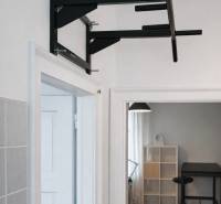 Polička na zdi, v pozadí místnost s podlahou s dřevěným dekorem.