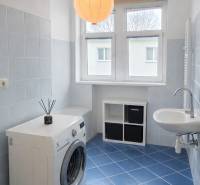 Koupelna v 2pokojovém bytě s pračkou, umyvadlem a modrou dlažbou.