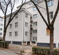 Bytový dům v Bratislavě na Jurajově dvoře, U staré prachárny. Čtyřpatrová budova, stromy, chodník.