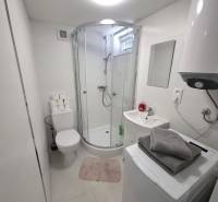 Koupelna s vanou, pračkou, bojlerem a umyvadlem v chatě. Minimalistický design.