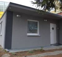 Chata s šedou fasádou v Bratislavě - Ružinově na Studené ulici, obklopená zelení.