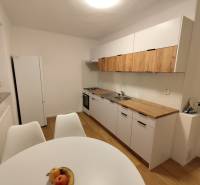 Kuchyně v 2-pokojovém bytě se světlými skříňkami a podlahou s dřevěným dekorem.