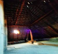 Podkroví v rodinném domě s dřevěným trámováním a oknem.