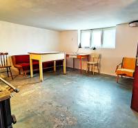 Sklep v rodinném domě s nábytkem a oknem, betonová podlaha.