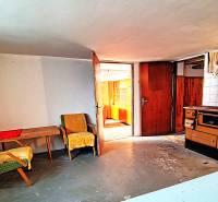 Pokoj v rodinném domě s křesly, stolem a starými kamny.