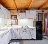 Kuchyně v chatě s dřevěným stropem a vintage skříněmi, útulné vybavení.