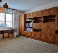 Rodinný dům má pracovnu s dřevěnou policovou stěnou, velkým stolem a kobercovou podlahou.
