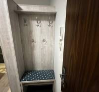 Vstupní chodba s věšáky a lavičkou v 2-pokojovém bytě.