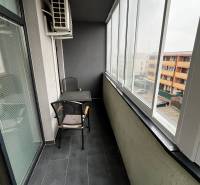 Zasklená lodžie 2-pokojového bytu na Holubej ulici v Senci s dlažbou a sezením.