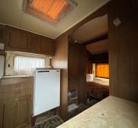 Interiér s podlahou s dřevěným dekorem, kuchyňskou linkou a postelí v Pozemky - bydlení.