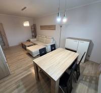 Obývací pokoj s podlahou s dřevěným dekorem, pohovkou a stolem ve 3pokojovém bytě.