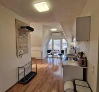 Interiér rodinného domu s kuchyní a jídelním koutem, podlaha s dřevěným dekorem.