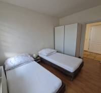 Pokoj v rodinném domě s dvěma postelemi, skříní a podlahou s dřevěným dekorem.