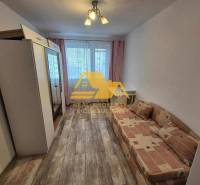 Pokoj v 3-pokojovém bytě s pohovkou, skříní a podlahou s dřevěným dekorem.