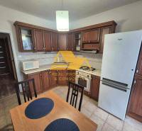 Kuchyně s tmavým dřevěným dekorem, sporákem a lednicí ve 3-pokojovém bytě.