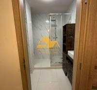 Koupelna se sprchovým koutem a umyvadlem v 2-pokojovém bytě, s obkladem ve světlých tónech.