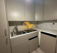 Kuchyně v 2pokojovém bytě s mramorovou deskou a šedými skříňkami.