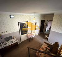 Interiér rodinného domu se vzorovanou tapetou, nábytkem a květinovou dekorací.