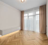 Obývací pokoj v 2pokojovém bytě s podlahou s dřevěným dekorem a bílým nábytkem.