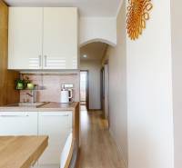 Kuchyňská linka s bílými skříňkami a podlahou s dřevěným dekorem v 3-pokojovém bytě.