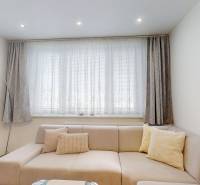 Obývací pokoj s pohovkou a závěsy ve 3pokojovém bytě.