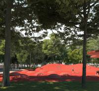 Park s červeným hřištěm na ulici Golianova v Trnavě obklopený stromy a lavičkami.