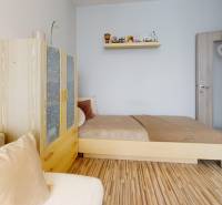 Pokoj s postelí, skříní a podlahou s dřevěným dekorem ve 3-pokojovém bytě.