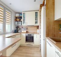 Kuchyně s podlahou s dřevěným dekorem, světlými skříňkami a výhledem v 3-pokojovém bytě.