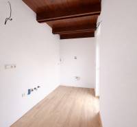 Interiér rodinného domu s podlahou s dřevěným dekorem a dřevěným trámovým stropem.